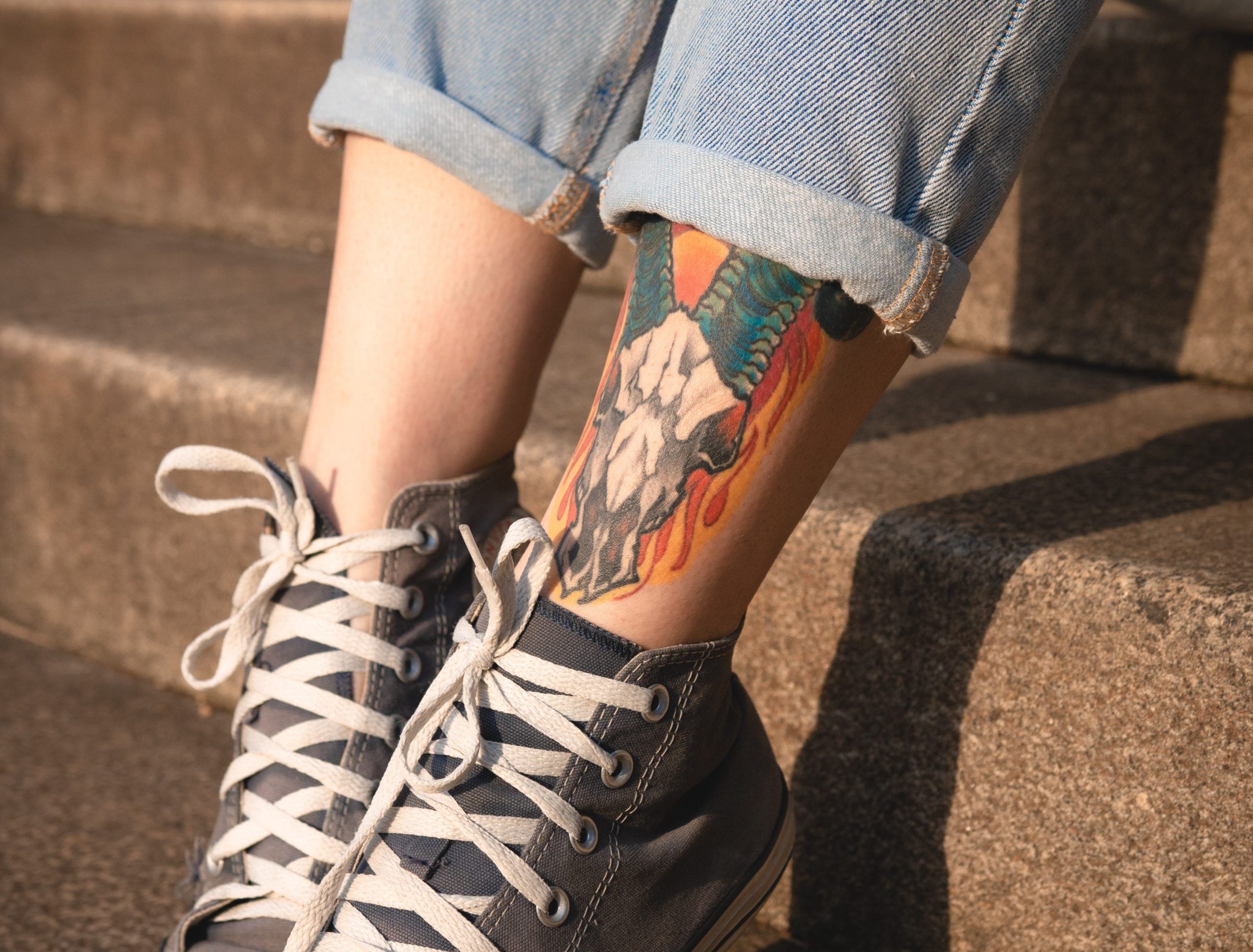 girl's legs with colour tattoo wearing converse